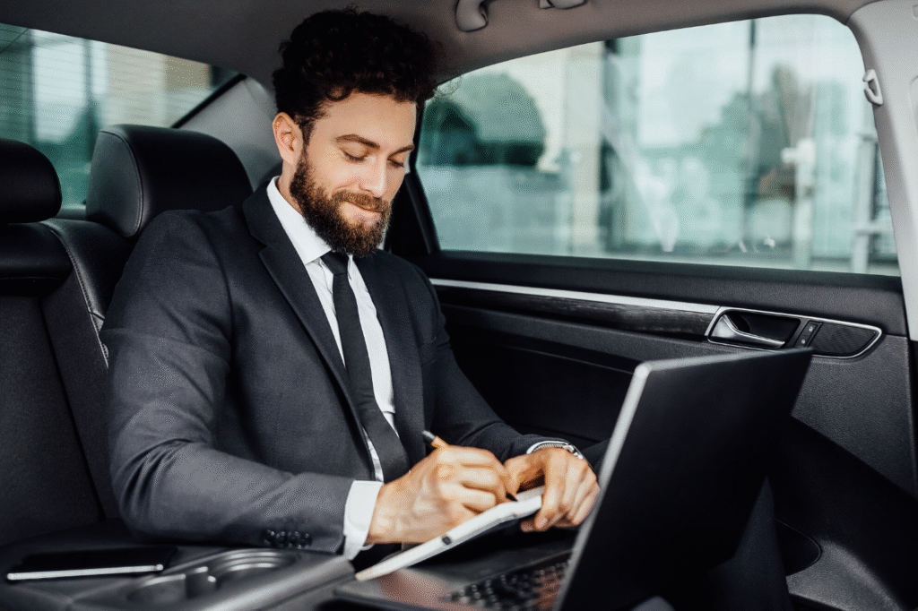 Businessman working in back seat of luxury car city-to-city private transfer switzerland